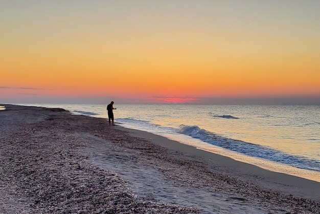 Pescatore al tramonto la sera in riva al mare