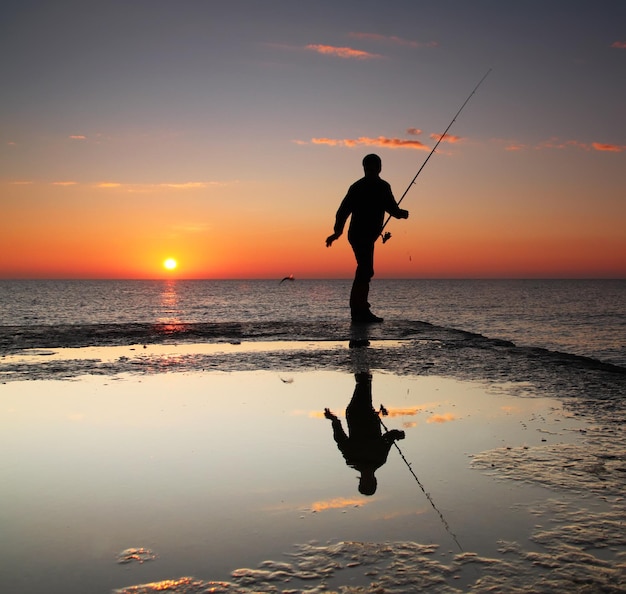 Pescatore all'alba sul mare