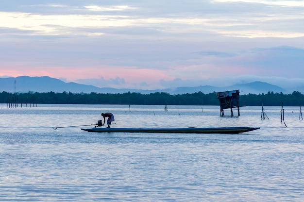 Pescatore che avvia il motore della barca di legno nel lago