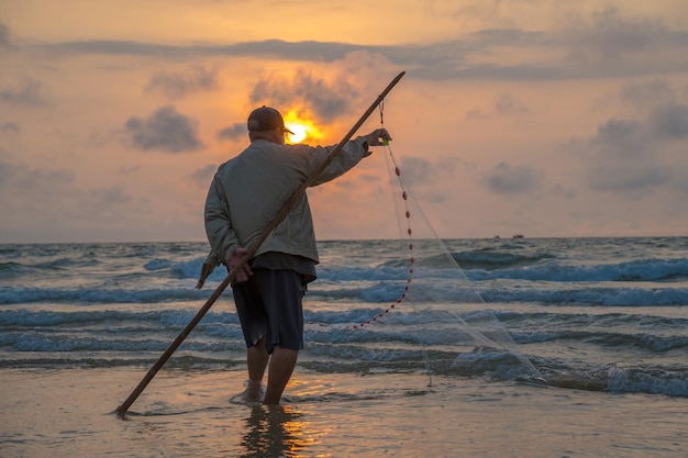 Pescatore che getta la sua rete all'alba o al tramonto I pescatori tradizionali preparano la rete da pesca