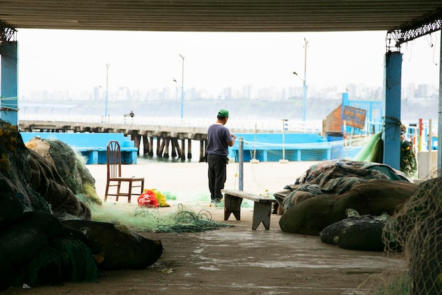 Pescatore che lavora con reti da pesca nel porto di Chorrios nella città di Lima in Perù