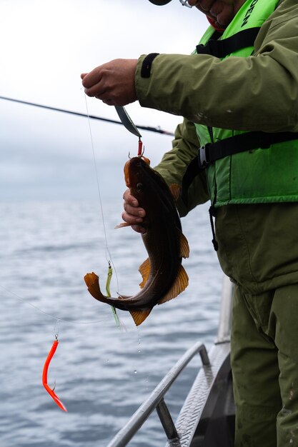 Pescatore che toglie il pesce dall'amo mentre pesca nella bellissima Norvegia