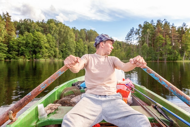 Pescatore con canne da pesca sta pescando in un gommone sul lago o sul fiume