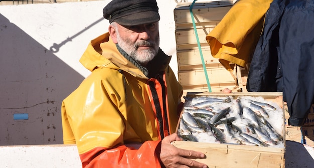 pescatore con una scatola di pesce all&#39;interno di una barca da pesca