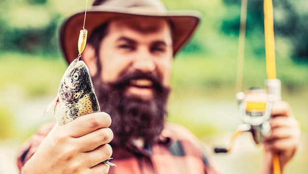 Pescatore e trota Sfondi di pesca L'uomo tiene in mano trote di pesce grosso Pescatore e trofeo di trote