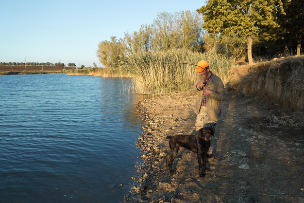 Pescatore in piedi sulla riva del fiume e cercando di catturare un pesce. Sport, ricreazione, stile di vita.