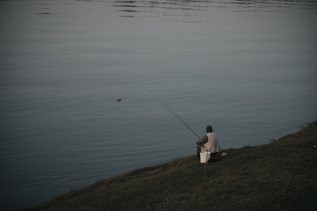 Pescatore seduto vicino al lago