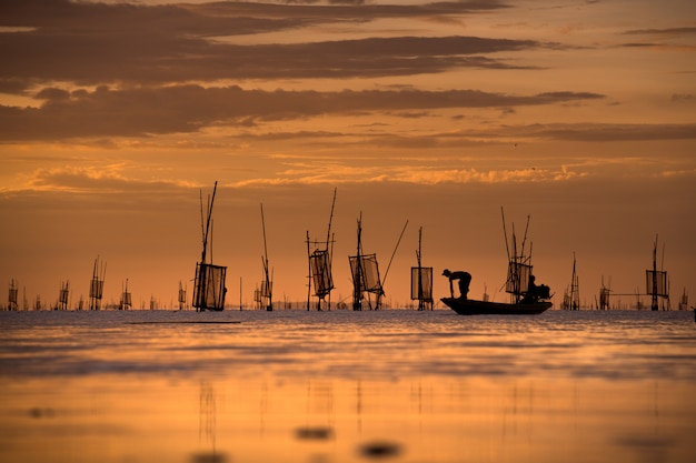 Pescatore sulla barca cattura pesci con tramonto