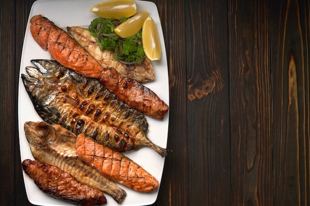 Pesce alla griglia su un piatto bianco con erbe e limone