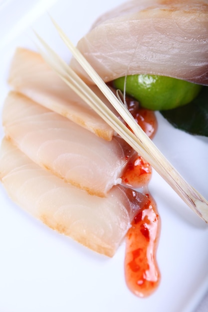 Pesce bianco crudo fresco decorato con salsa, lime e bastoncino. Avvicinamento