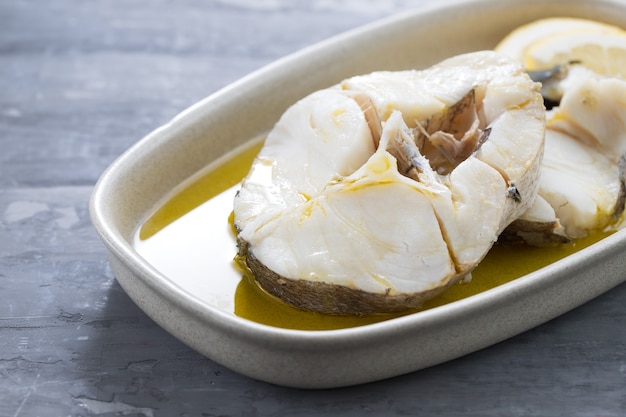 Pesce bollito con olio d'oliva in piatto su ceramica