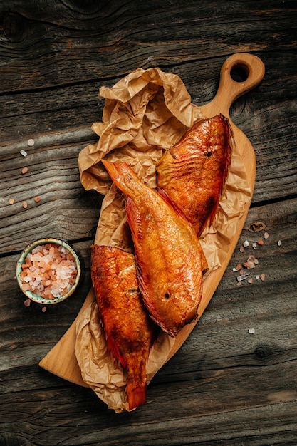 Pesce branzino affumicato caldo sul tagliere di legno. immagine verticale. vista dall'alto. posto per il testo.