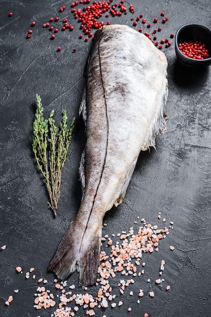 Pesce crudo dell'eglefino senza testa. Sfondo nero.