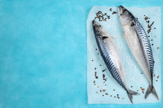 Pesce crudo della makrelle con gli ingredienti per la cottura sul blu.