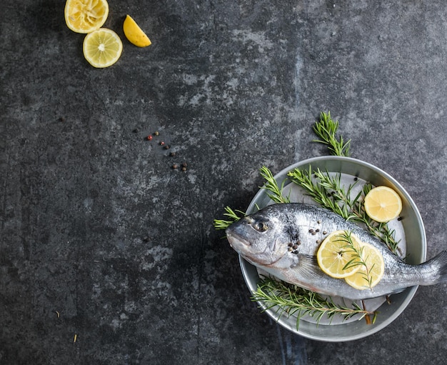 Pesce crudo di dorado con spezie Dorado e ingredienti per cucinare su un tavolo