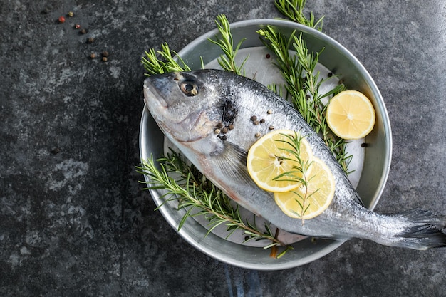 Pesce crudo di dorado con spezie Dorado e ingredienti per cucinare su un tavolo