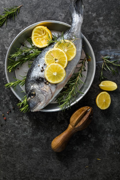 Pesce crudo di dorado con spezie Dorado e ingredienti per cucinare su un tavolo