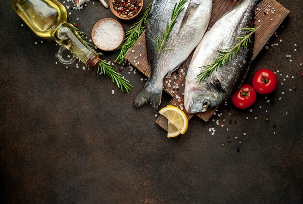 Pesce crudo di dorado con spezie e ingredienti pomodoro, razmorin, olio di semi di girasole, limone su uno sfondo di pietra con spazio di copia per il testo