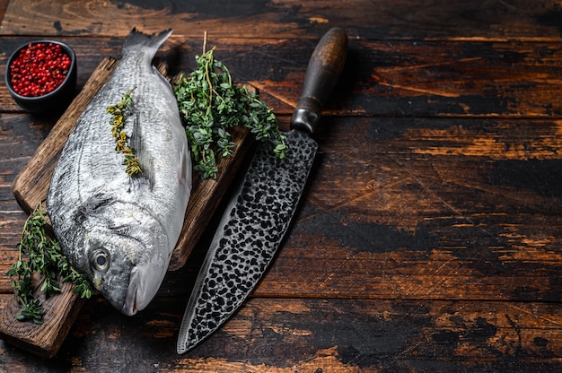 Pesce crudo di dorado su un tagliere con coltello.