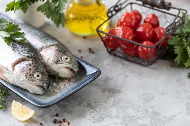 pesce crudo trota iridea su un piatto, verdure e verdure fresche per preparare cibi sani e gustosi. Dieta sana e delizioso concetto culinario.