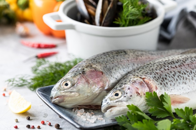 pesce crudo trota iridea su un piatto, verdure e verdure fresche per preparare cibi sani e gustosi.