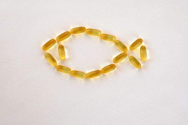 Pesce dalle capsule d'oro omega 3 su sfondo bianco