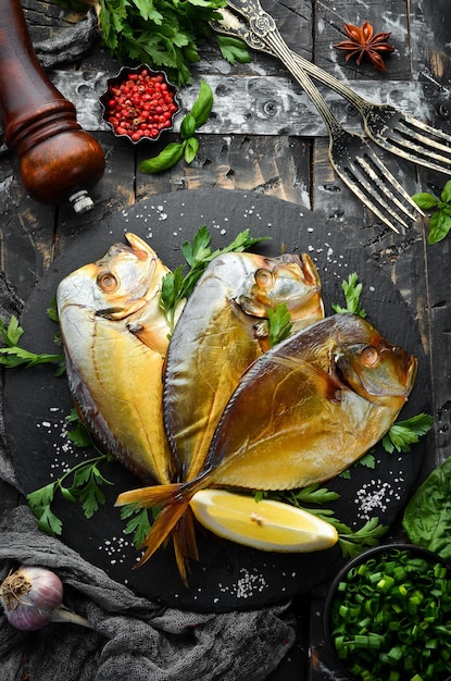 Pesce di mare affumicato Vomer con prezzemolo su una lastra di pietra nera. Vista dall'alto. Spazio libero per il tuo testo.