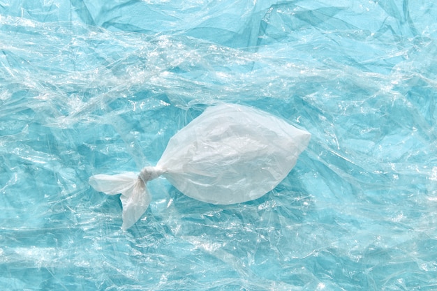 Pesce di plastica bianco su un politene trasparente con spazio di copia. Problema ecologico dell'inquinamento ambientale degli oceani.
