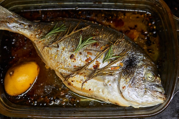 Pesce dorado al forno con limone rosmarino e altre erbe Vista dall'alto Foto di alta qualità