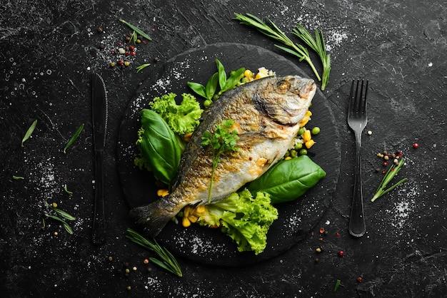 Pesce Dorado al forno con riso e verdure su un piatto nero Vista dall'alto Spazio libero per il testo