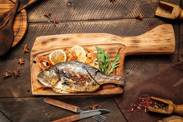 Pesce dorado alla griglia su una tavola di legno