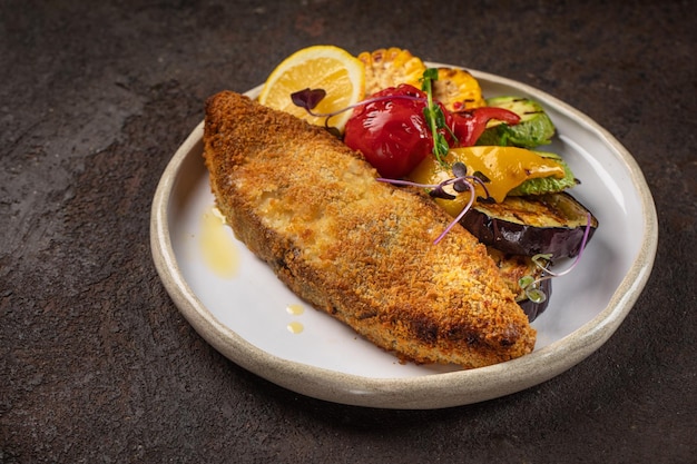 Pesce e filetto di pesce fritto piatto bianco e verdure su sfondo nero