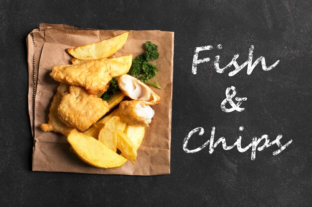 Pesce e patate fritte britannico tradizionale sulla superficie scura