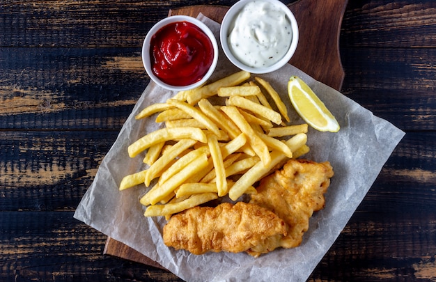 Pesce e patatine fritte su un fondo di legno. Fast food britannico. Ricette. Spuntino alla birra. Cucina inglese.