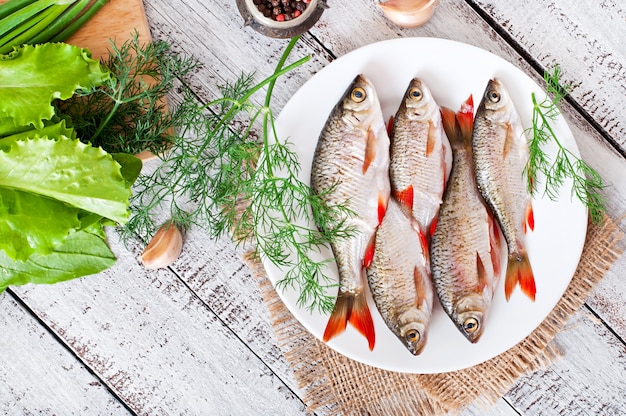 pesce fresco con rosmarino in un piatto sul tavolo di legno