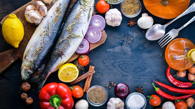 Pesce fresco con verdure, spezie e olio Su fondo di legno nero Spazio libero per il testo Vista dall'alto