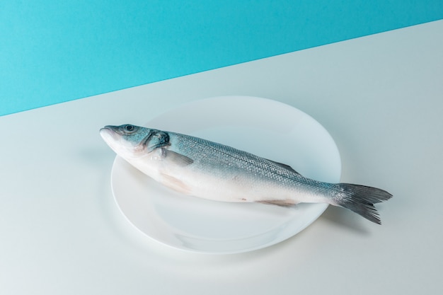 Pesce fresco crudo della spigola su un piatto bianco