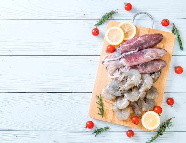 pesce fresco crudo (gamberetti, calamari) su tavola di legno