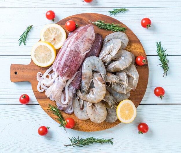 pesce fresco crudo (gamberetti, calamari) su tavola di legno