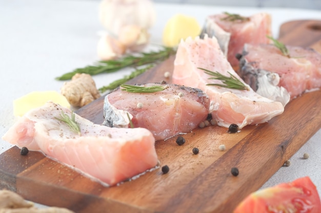 Pesce fresco crudo su un tagliere per la preparazione per la cottura sul tavolo