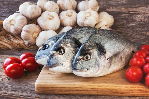 Pesce fresco di Dorada sul tagliere di legno con le verdure tonificate