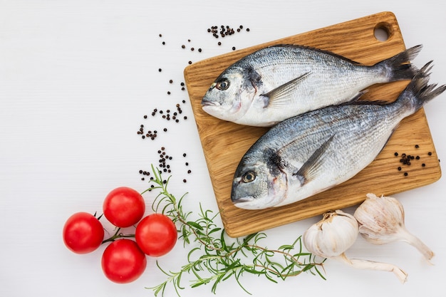 Pesce fresco di dorado sul tagliere di legno con aglio