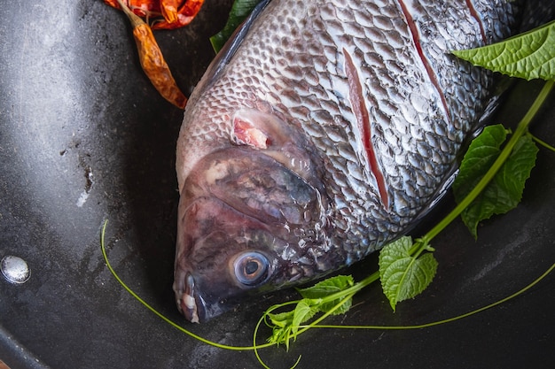 Pesce fresco in padella e spezie per cucinare