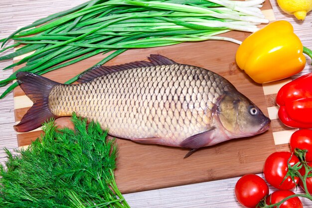 Pesce fresco su una tavola da cucina con verdure.