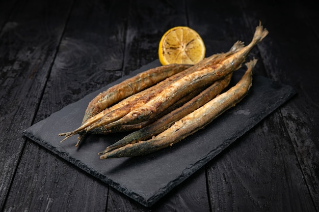 Pesce fritto con limone su un tavolo scuro