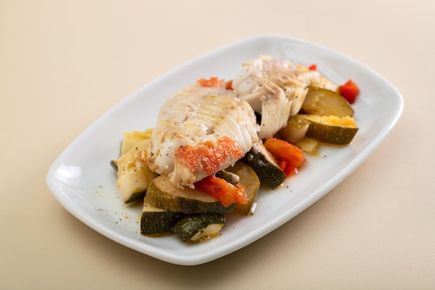 Pesce fritto con verdure al forno su piatto bianco