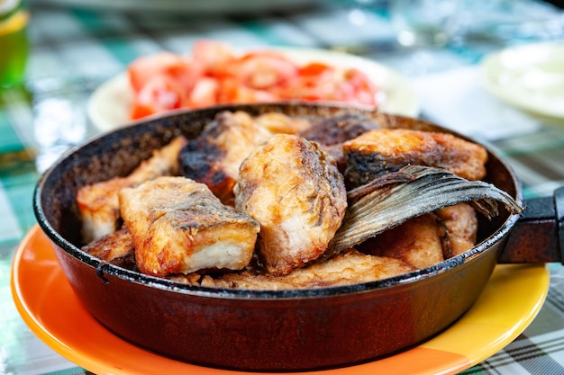 Pesce fritto in padella sul tavolo Concetto di fast food di cibo di strada