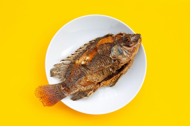 Pesce fritto in piatto bianco su fondo giallo