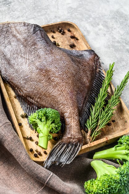 Pesce John Dory su un vassoio di legno con rosmarino e broccoli.