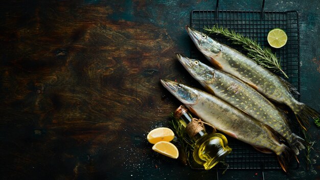 Pesce luccio con spezie ed erbe aromatiche. Preparazione. Su uno sfondo scuro della cucina. Vista dall'alto.